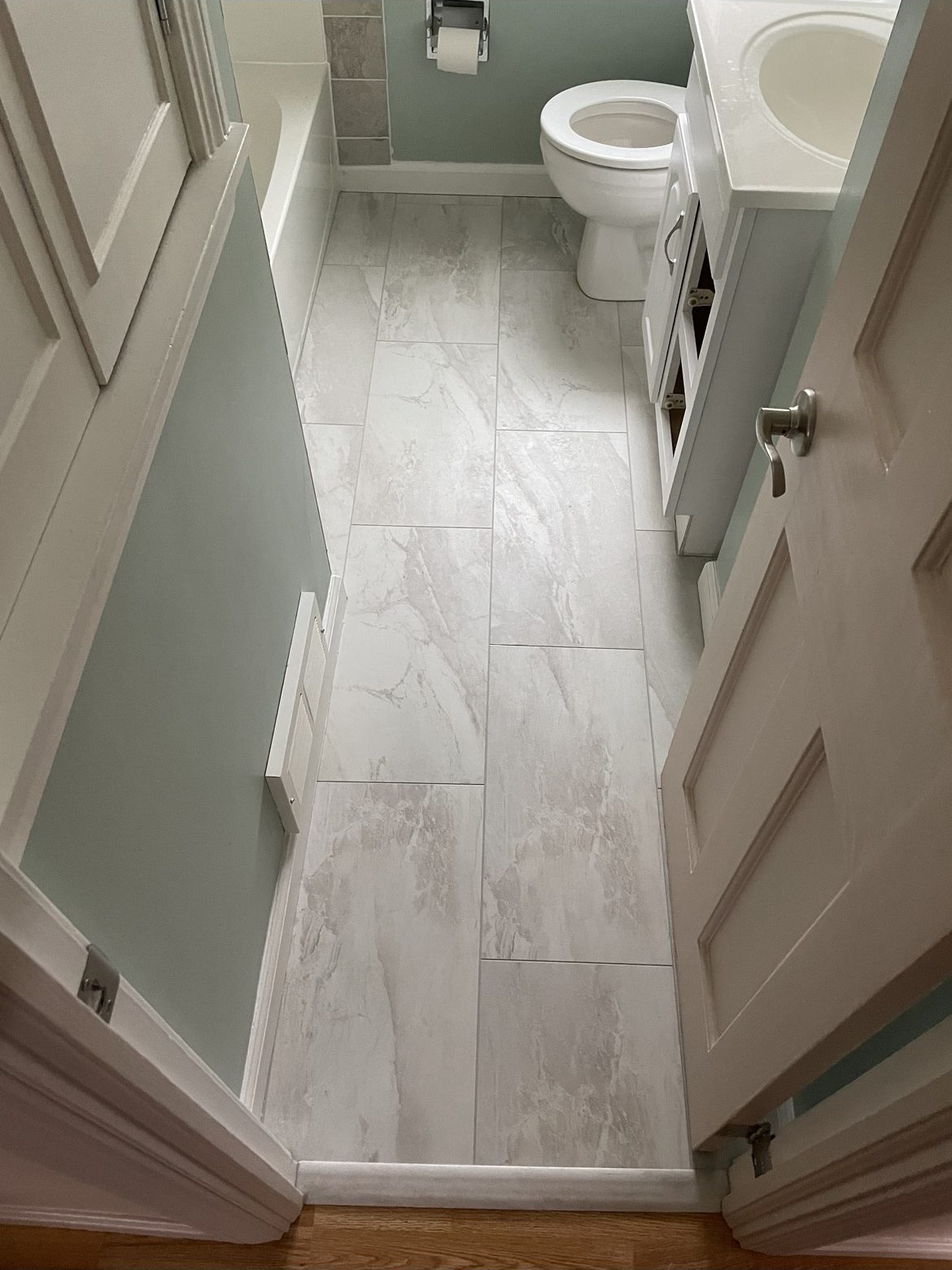 Bathroom floor tile update with large-format white marble tile and new toilet area in Cuyahoga County
