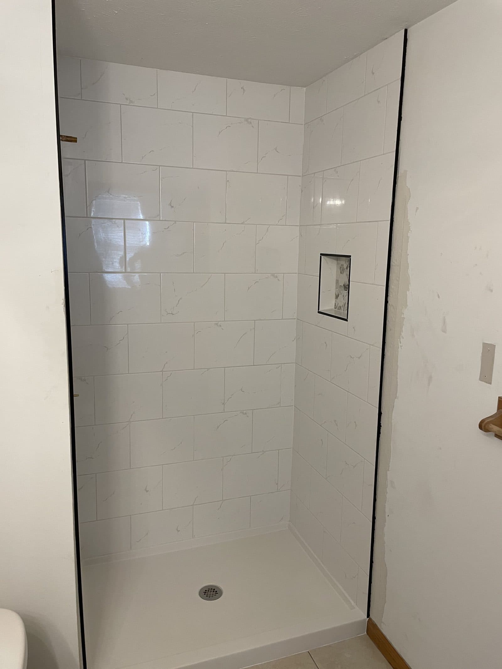 Walk-in shower with white Calacatta marble subway tile and built-in niche in Northeast Ohio