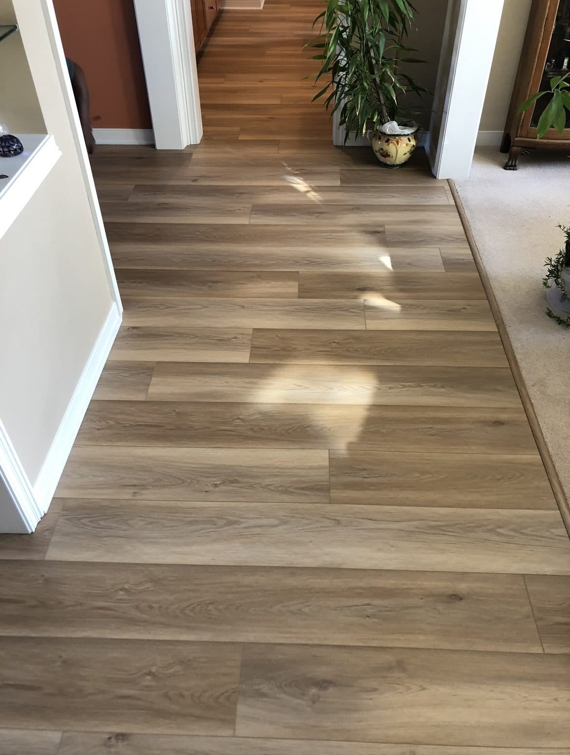 Light oak luxury vinyl plank flooring installation in hallway and living area in Cuyahoga County home