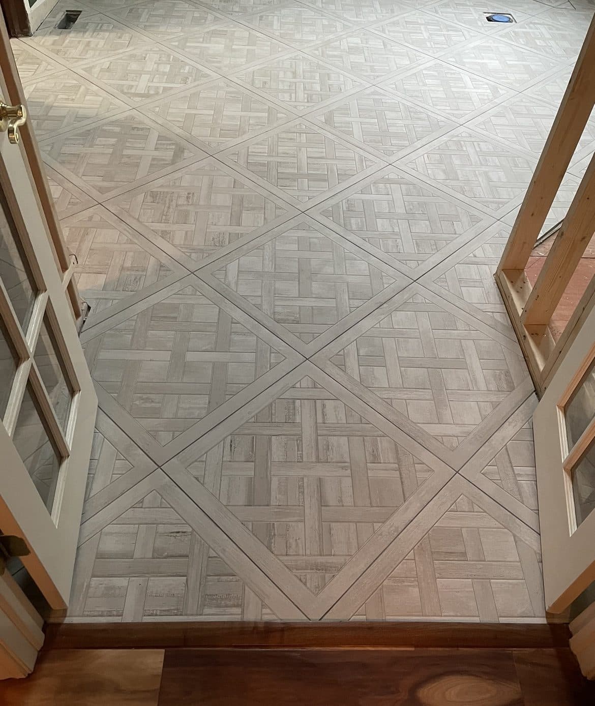 Decorative diagonal basket-weave tile entryway installation with hardwood flooring transition in Lake County Ohio