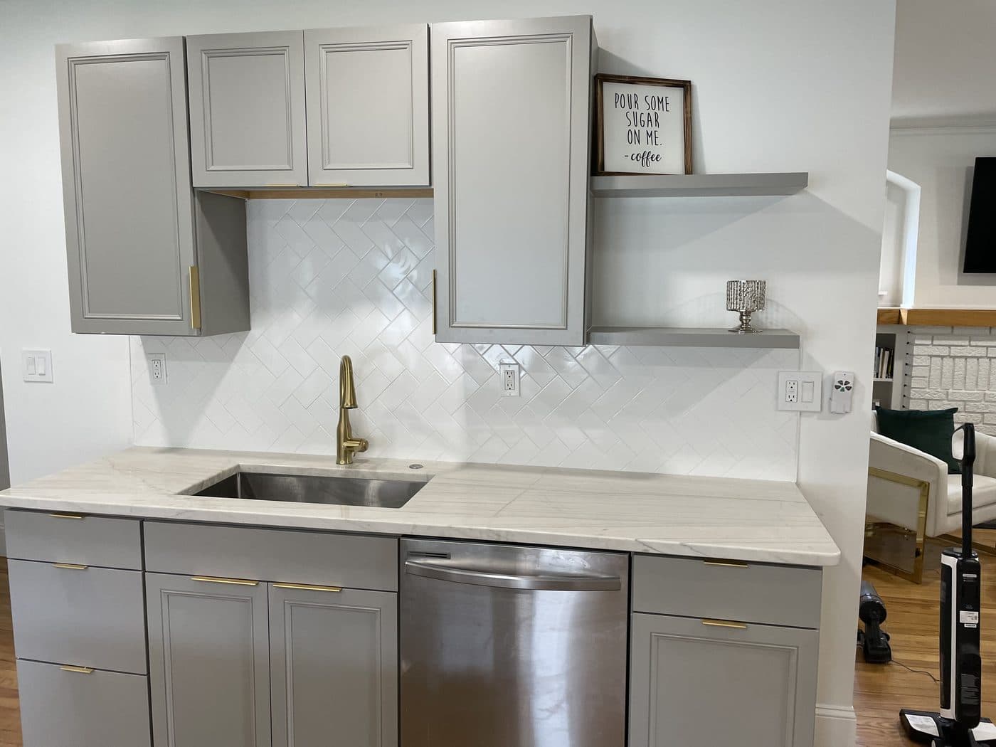 Kitchen remodel with grey raised-panel cabinets, white herringbone tile backsplash, gold hardware, and marble countertops in Cuyahoga County