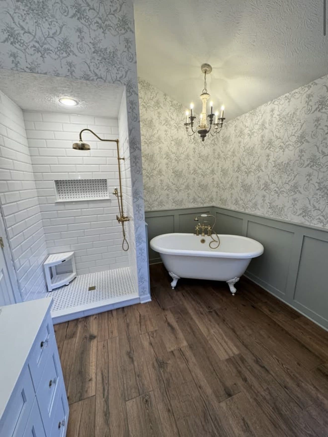Luxury master bathroom remodel with clawfoot soaking tub, white subway tile shower, vintage brass fixtures, crystal chandelier, and floral wallpaper in Lake County Ohio