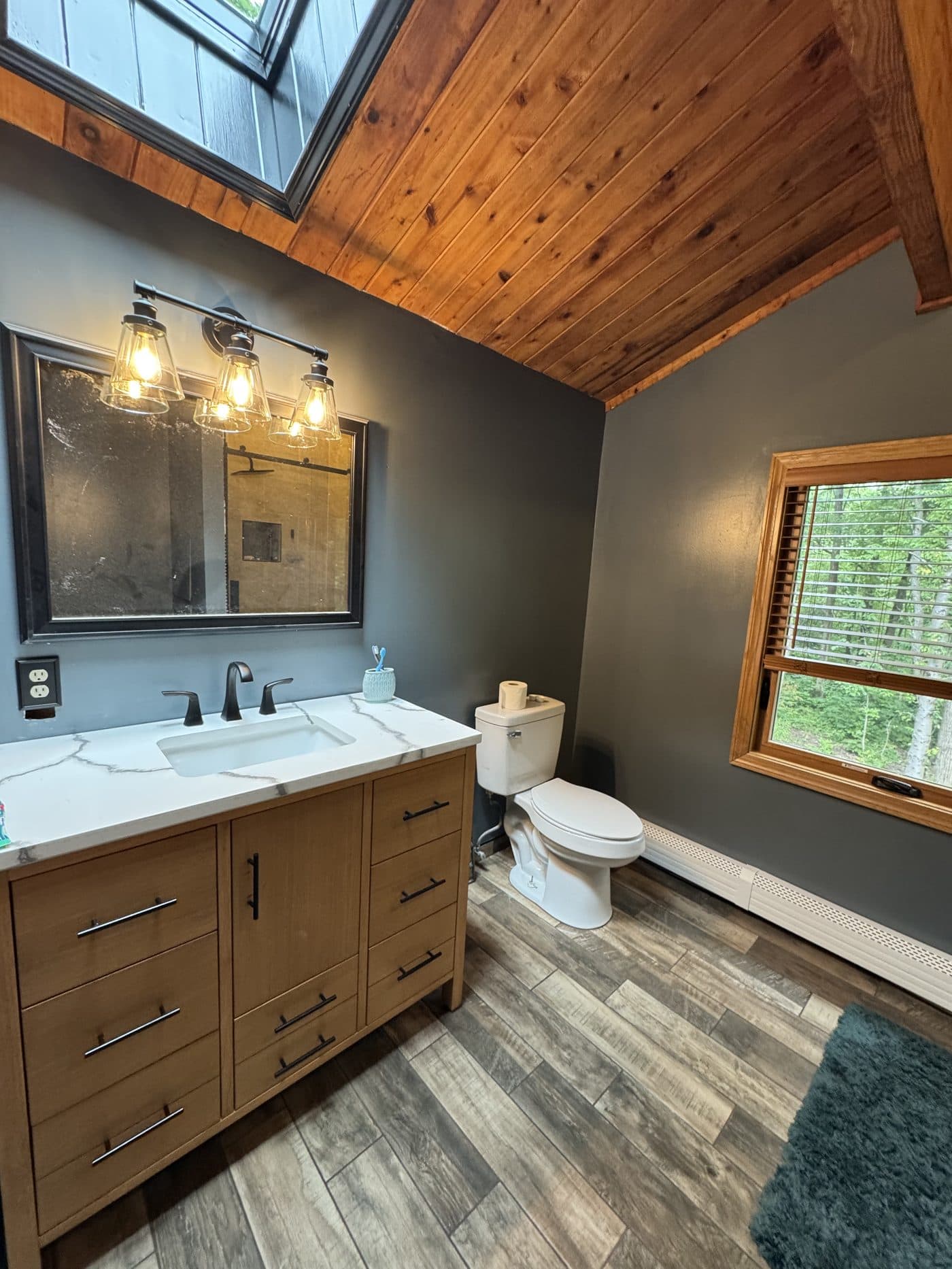 Rustic bathroom remodel with wood-plank ceiling, skylight, dark slate tile shower, and walnut vanity in Lake County Ohio