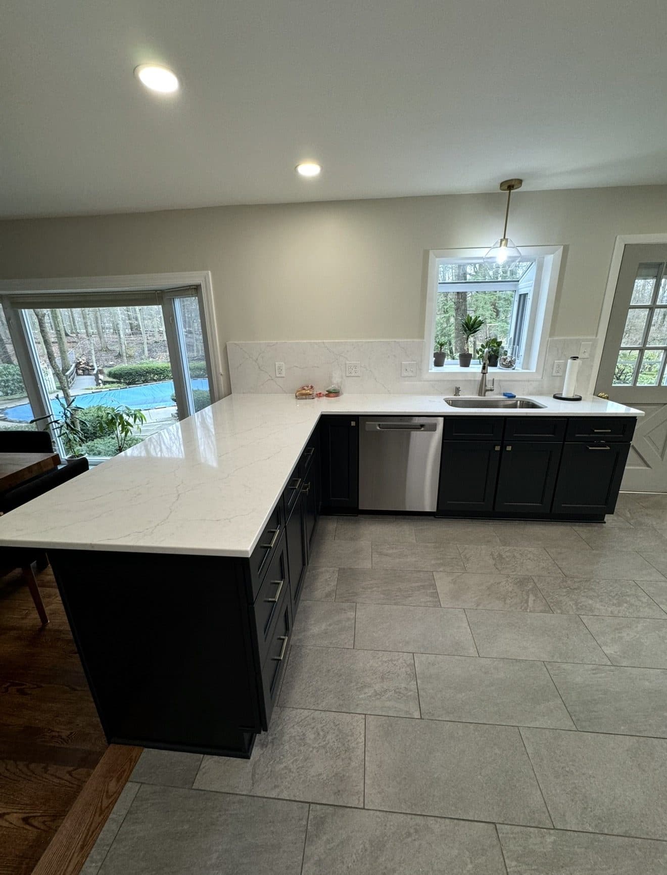 Kitchen remodel with dark navy shaker cabinets, Calacatta quartz countertops, full-slab marble backsplash, and large island in Cuyahoga County