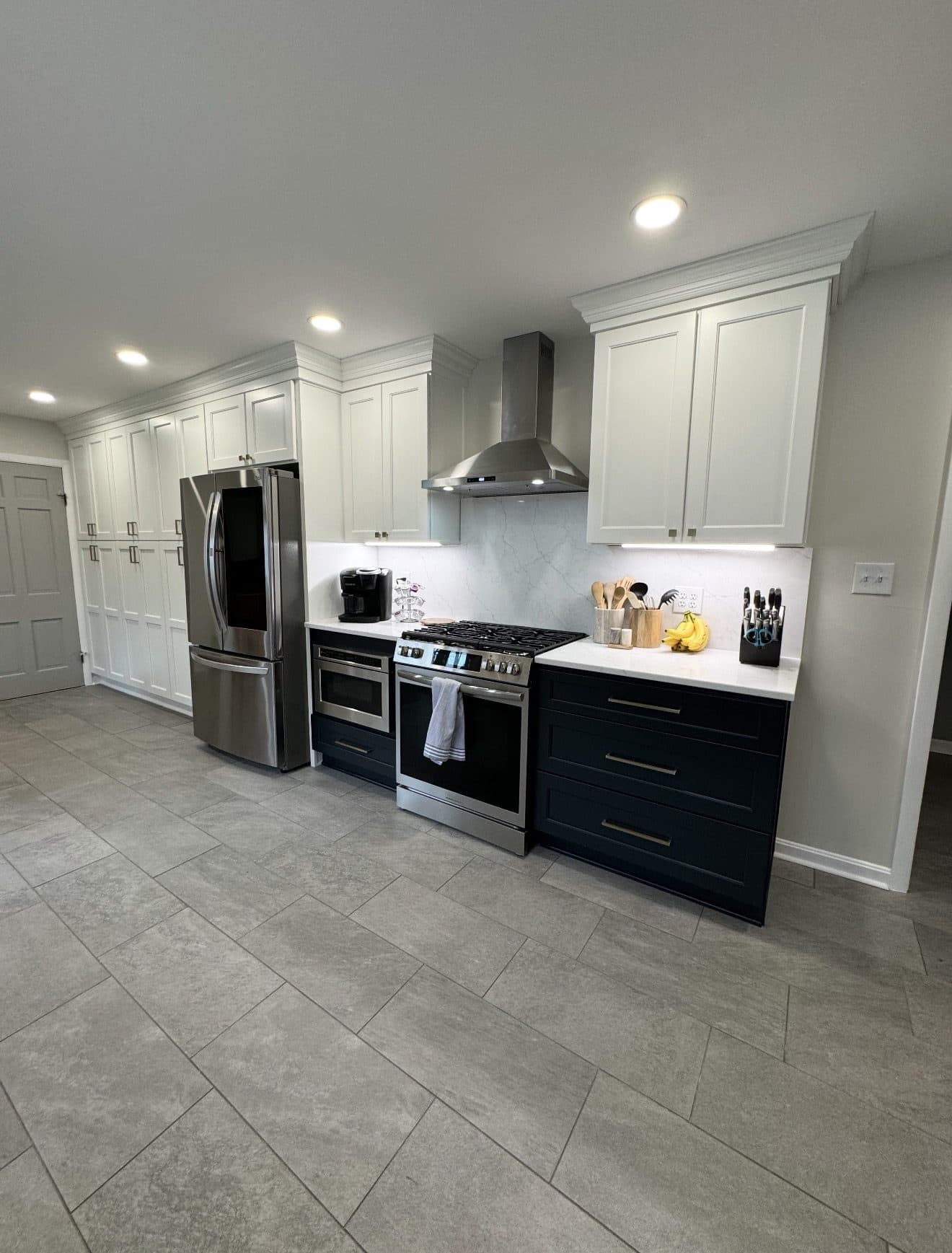 Two-tone kitchen remodel with white upper and navy lower cabinets, Calacatta marble slab backsplash, and quartz countertops in Lake County Ohio