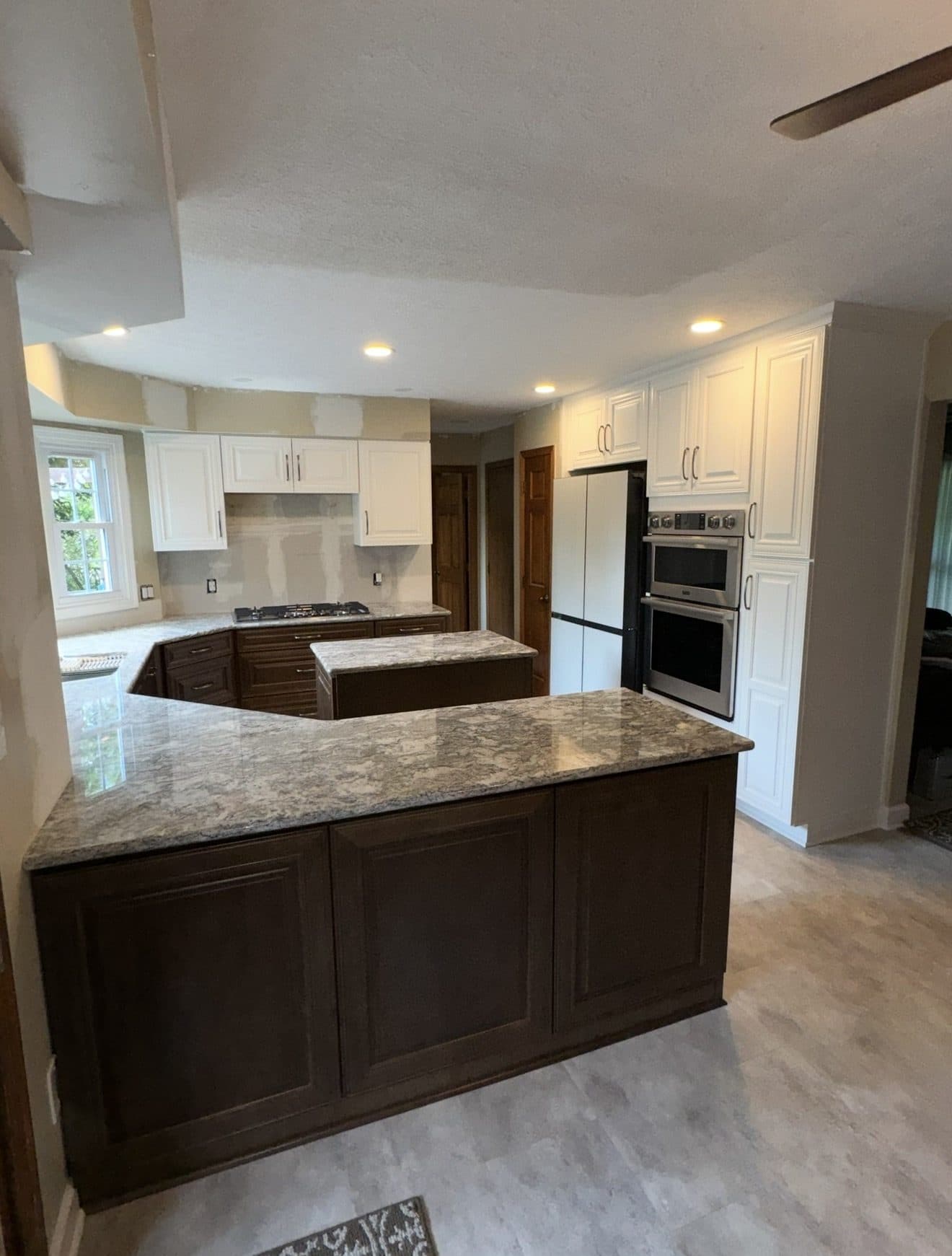 Kitchen remodel with dark espresso lower cabinets, white upper cabinets, grey veined granite countertops, and double wall ovens in Northeast Ohio