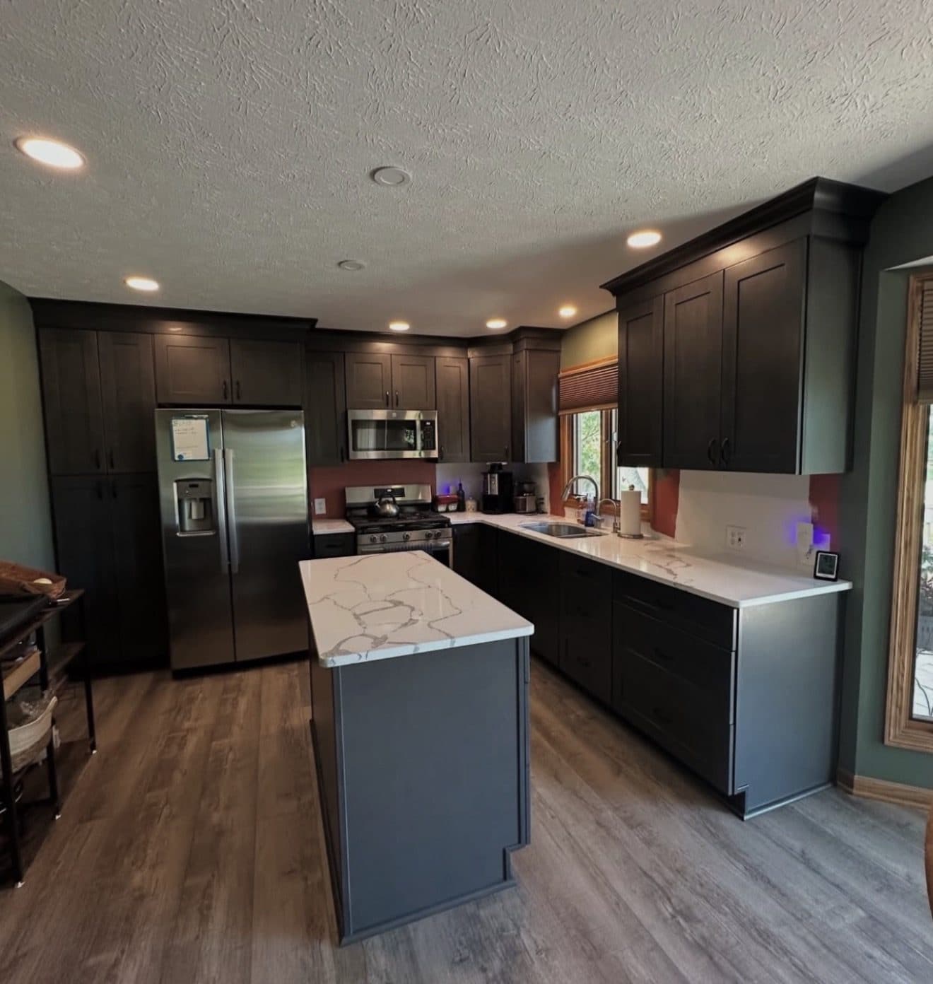 Kitchen remodel with dark espresso shaker cabinets, Calacatta quartz island, and light luxury vinyl plank flooring in Cuyahoga County