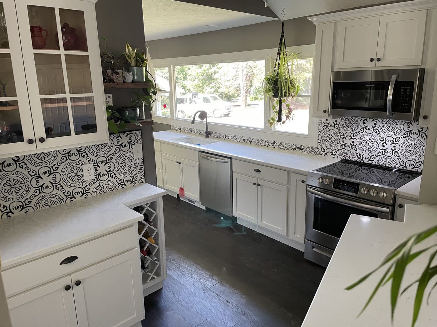 Kitchen remodel with white shaker cabinets, dramatic black-and-white geometric cement tile backsplash, and dark hardwood floors in Lake County Ohio