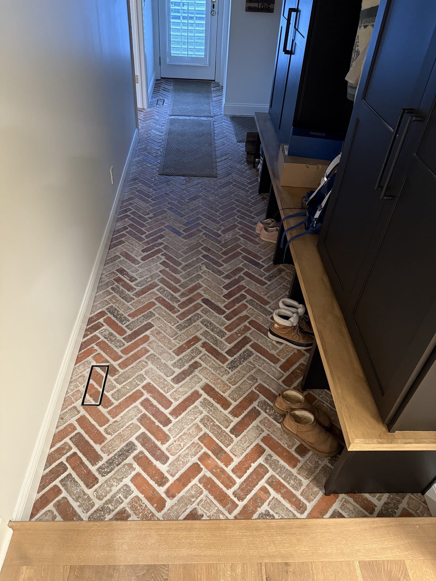 Red brick herringbone pattern floor tile installation in mudroom and entryway in Cuyahoga County home