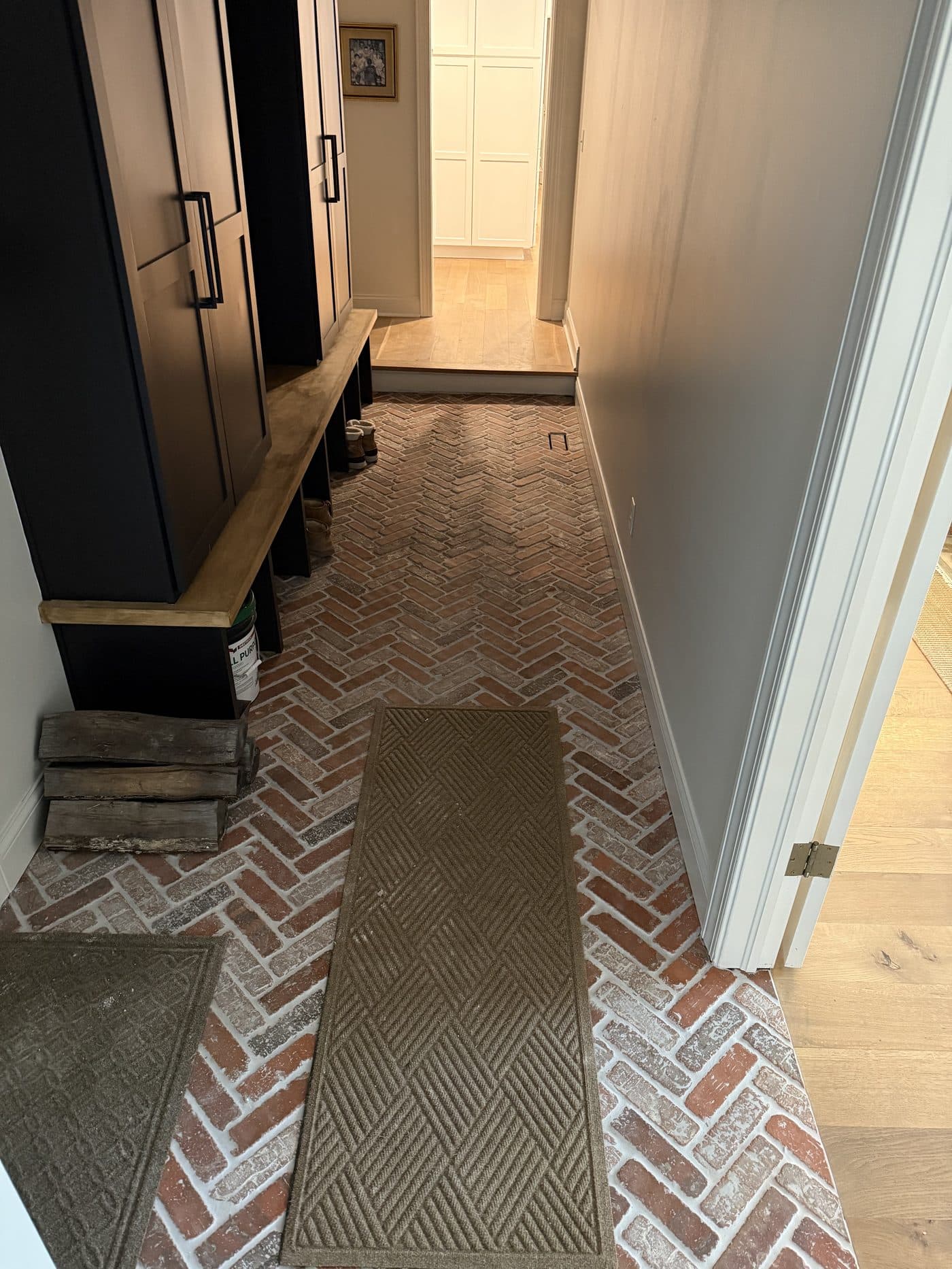 Red brick herringbone entryway tile with custom built-in bench and dark shaker cabinetry in Northeast Ohio home