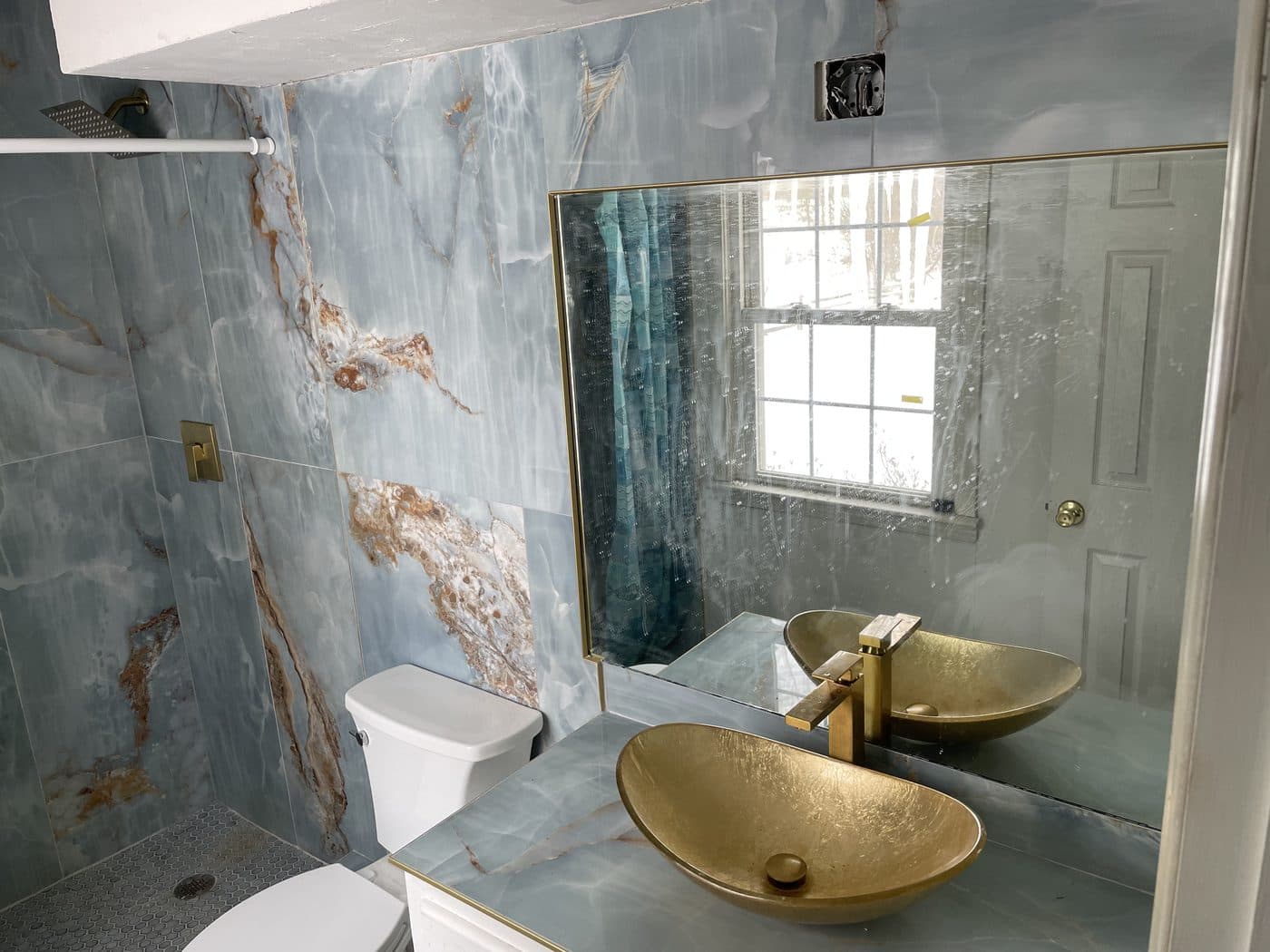 Full bathroom remodel with bold blue onyx-look porcelain tile, double vanity with quartz countertops, and frameless glass shower in Northeast Ohio