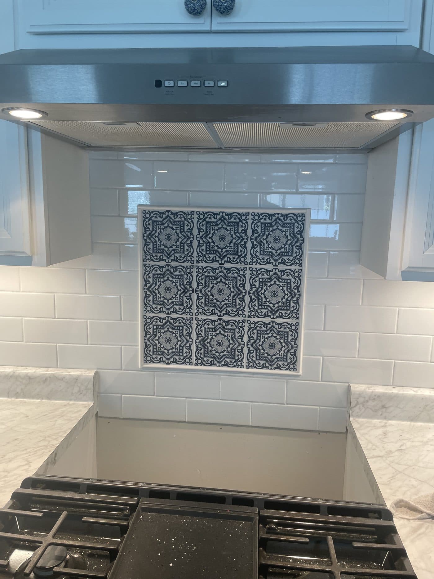 Kitchen remodel with white subway tile backsplash and bold navy blue Moroccan accent tile at range in Lake County Ohio