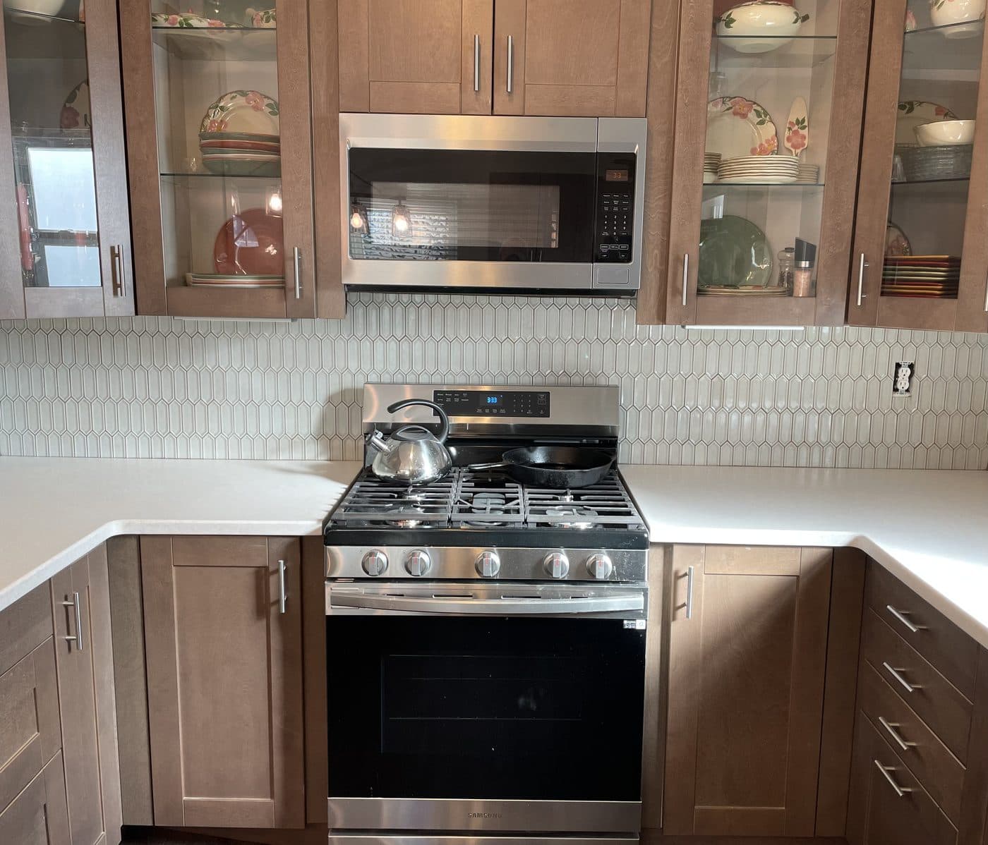 Kitchen remodel with warm brown shaker cabinets, glass-front upper cabinets, and ivory picket mosaic backsplash in Northeast Ohio