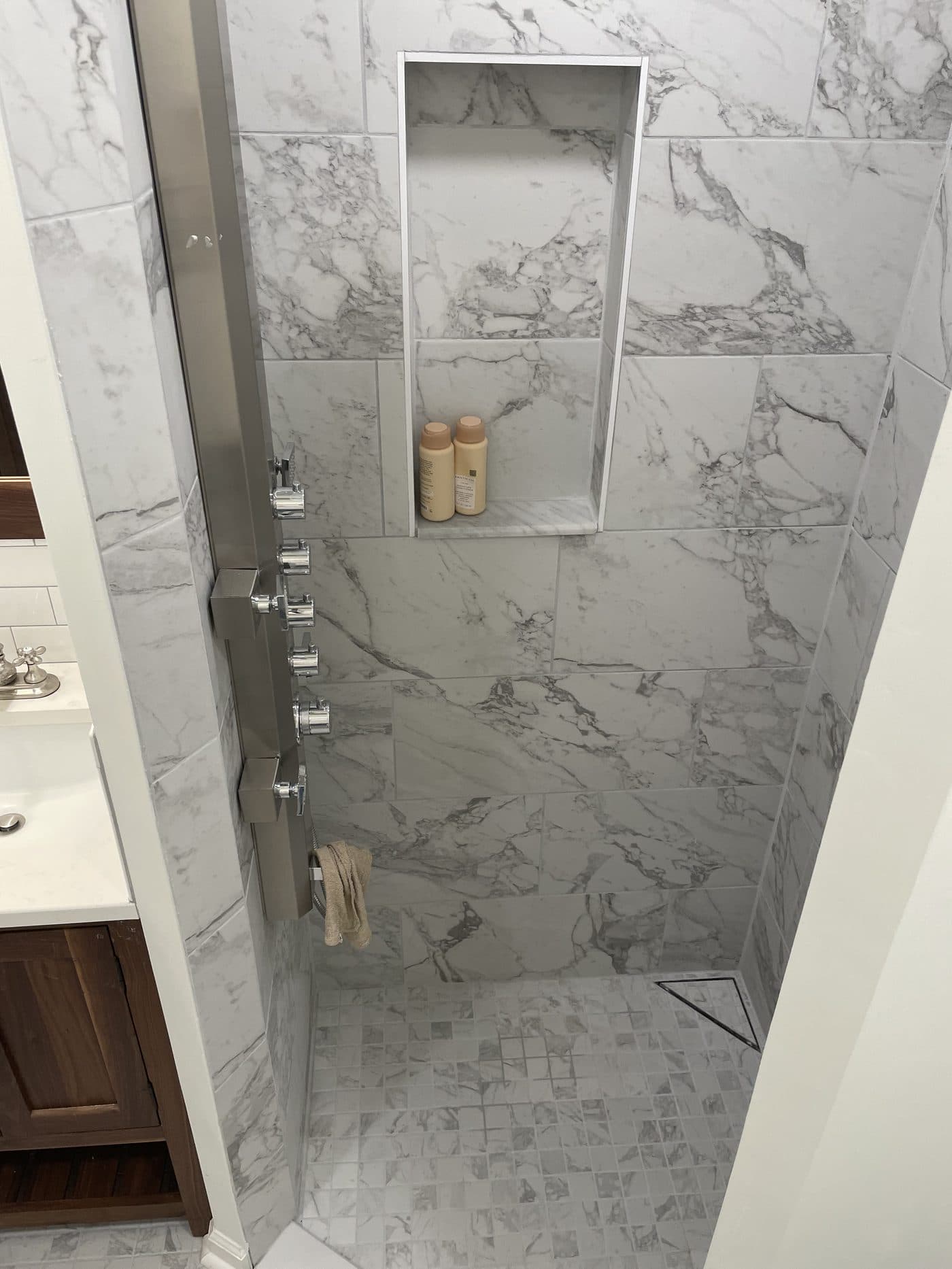 Carrara marble large-format shower with multiple body jets, built-in niche, and bench in Cuyahoga County