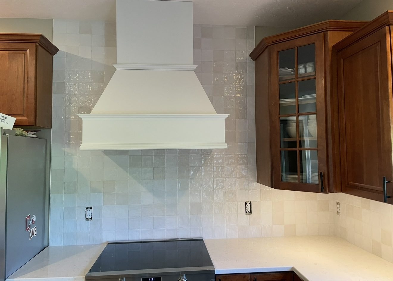 Kitchen range hood and backsplash remodel with white zellige-style square tile and dark wood cabinets in Northeast Ohio