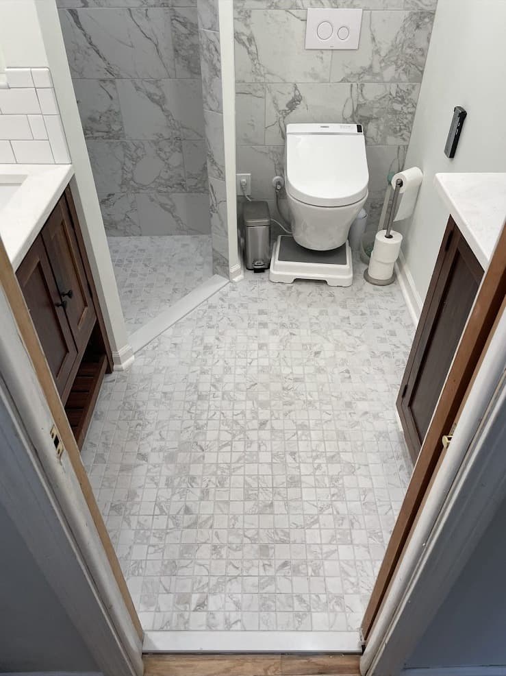 Bathroom remodel with Carrara marble mosaic floor tile and large-format marble accent wall in Cuyahoga County